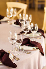 Festive wedding table setting with flowers, napkins, cutlery, glasses, bright summer table decor. Wedding decor