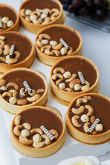 Chocolate caramel tart with nuts in a white plate on a wooden background
