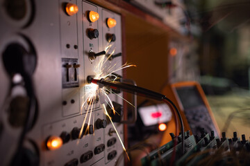 Electronic sparks scatter quickly and sharply from a short circuit on technological equipment in...