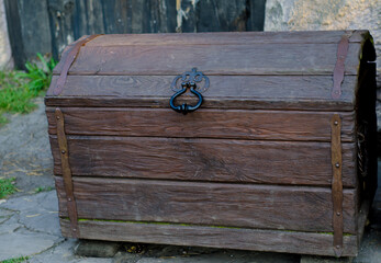 wooden chest upholstered with forged details with  metal handle stands on  street.