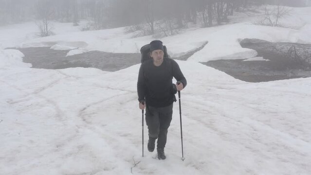 Solitary hiker walking alone in the snow in cold wintry wilderness