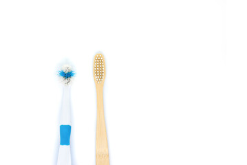 an eco-friendly bamboo toothbrush lies next to an old plastic brush on a white background. Flat lay, top view. Copy space. Zero waste personal care product, dental care