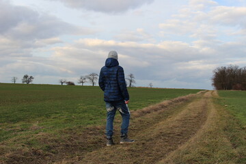Young boy walking on a path between fields