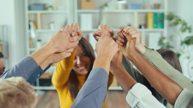 Close-up. A Group of Happy Multiracial People Holding Hands, Lifting Them Up in a Psychological Therapy Session, Smiling, Celebrating Common Progress and Supporting Each Other. Rehabilitation Concept.