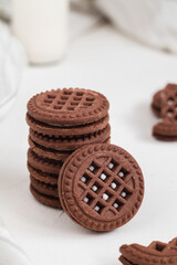 Round chocolate sandwich cookies close up with cream fiiling on a white table.