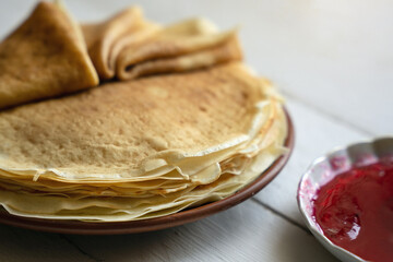 Crepes, thin pancakes on a plate on a white wooden table