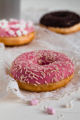 Sweet round donut with pink glaze and white sprinkles. Doughnut close up. Side view. Sweet bakery concept.