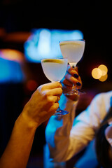 girls clink glasses with a cocktail