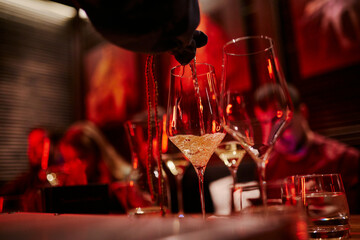 bartender pouring white wine in red room