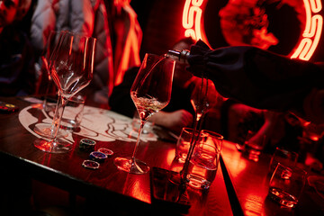 bartender pouring white wine in red room