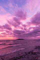Shore of Trasimeno lake Umbria, Italy with surreal purple clouds at dusk and island at the distance