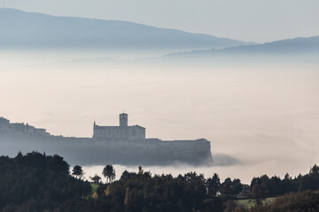 Surreal view of S. Francis church Assisi Italy above a sea of fog