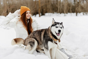 Happy young woman outdoors in a field in winter walking with a dog Lifestyle
