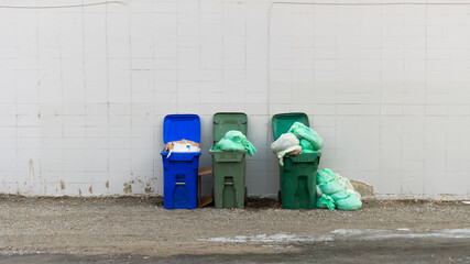 Green overflowing public garbage bins and blue recycling containers. Litter, trash, and plastic...