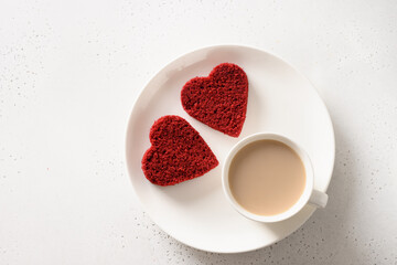 Valentine's day breakfast with heart-shaped two red velvet cake and latte coffee for on white table. View from above.