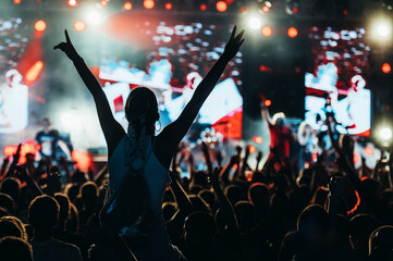 Silhouette of a woman with raised hands on a concert