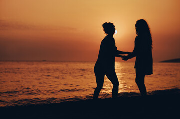 Attractive friends enjoying vacation together on the beach and having fun on a sunset