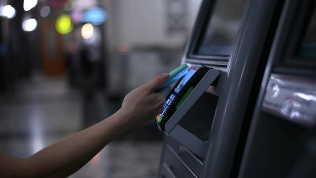 A woman pays with a mobile phone at a self-service checkout to buy train tickets. 