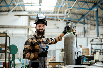Worker with a welding machine at workshop. - obrazy, fototapety, plakaty