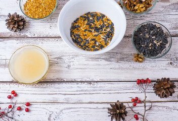 Food for birds for the winter. Seeds, millet, nuts, ghee in a bowl for making a feeder on a wooden white background.