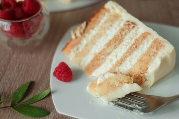 White, layered, multi-layer cake from biscuit smeared with cream, round shape, white cream inside, a piece is cut, a piece of cake with a fork.