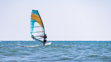 A man controls a sailboard at sea: one of the best remedies for a pandemic is windsurfing, and no mask is needed!