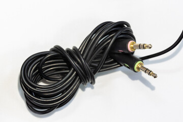 Black cable of microphone and earphone on isolated background. The end of the cable has thin, stereo, male headphone and microphone jacks.
