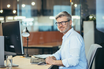 Portrait of an experienced male accountant, businessman working in a modern office at the computer