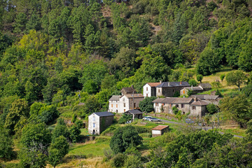 Village aux maisons blanches accroché au flanc d'une montagne boisée et agricole. Cévennes France. © fred.do.photo