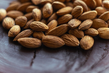 Close up almonds on dark wooden table. Organic health protein vegetarian food. Background copy space