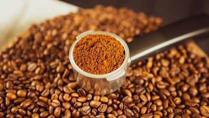 Ground coffee in portafilter on wooden board with coffee beans. Freshly ground coffee in filter holder and roasted beans for preparation of fragrant drink.