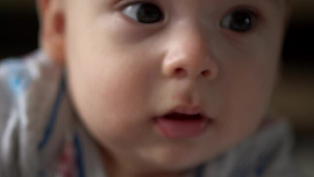 Newborn Active Baby Cute Smiling Teethless Face Portrait Early Days On Stomach Developing Neck Control. 5 Months Child On White Bed Looking on Camera. Infant, Childbirth, Parenthood, Beginning Concept