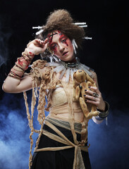 Young blond woman with creative make up and hairstyle holding little rabbit. Halloween theme.