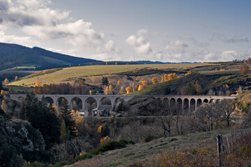 Viaduc de voix ferré permettant au train de tarversé la vallée et les paysages d'automne. Montagne des Cévennes en France.