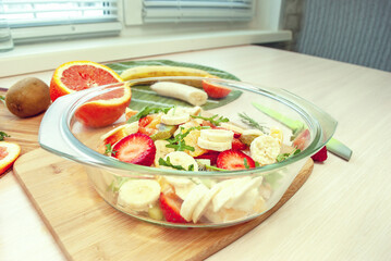 Fruit salad in a plate with sliced strawberries, kiwi, banana, orange and tangerine.