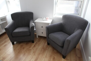 Two cozy grey armchairs, standing on wooden floor in an authentic apartment room or loft