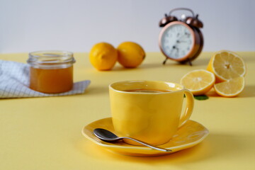 Breakfast - hot drink with honey or jam on a yellow background. In the background is an alarm clock that shows morning time - 7 hours