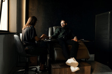 a satisfied man with a beard sits in a leather chair and is given a man's manicure. the concept of male manicure.