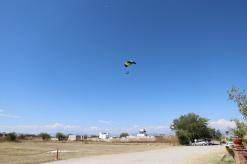 Skydiving. A skydiver is landing on the field.