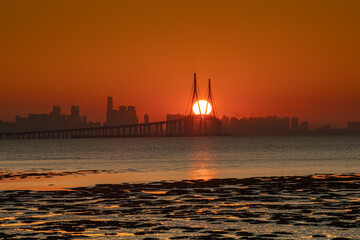 The sun rising through the bridge across the sea

