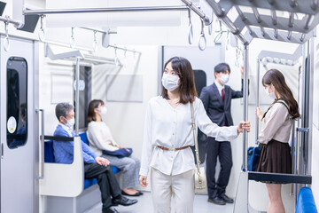 マスクをして電車移動をする若い女性