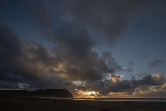 An image of a sun burst at sunset and Tillamook Head headland and the beach at Seaside Oregon.