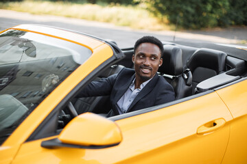 Car side window. Young handsome bearded African businessman driver happy smiling driving sport...