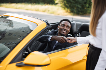 Young handsome African businessman in a Car Rental Service. Test Drive Concept. Young African...