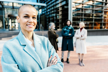 Happy smiling professional manager woman with crossed arms standing in building exterior - Portrait...