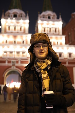 Happy smiling young men portrait in Red Square, Moscow. A men in the city is holding a coffee.