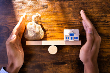 Closeup Of Model Home And Money Balancing