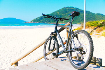 Bike on beach. Bike leaning at wooden fence at the beach, Praia Brava, Florianópolis, Southern Brazil   
