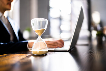 Hourglass On Desk. Running Late With Invoice