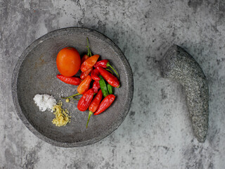 top view of red chilies, tomatoes, and seasonings in a mortar ready to make chili sauce. cooking...